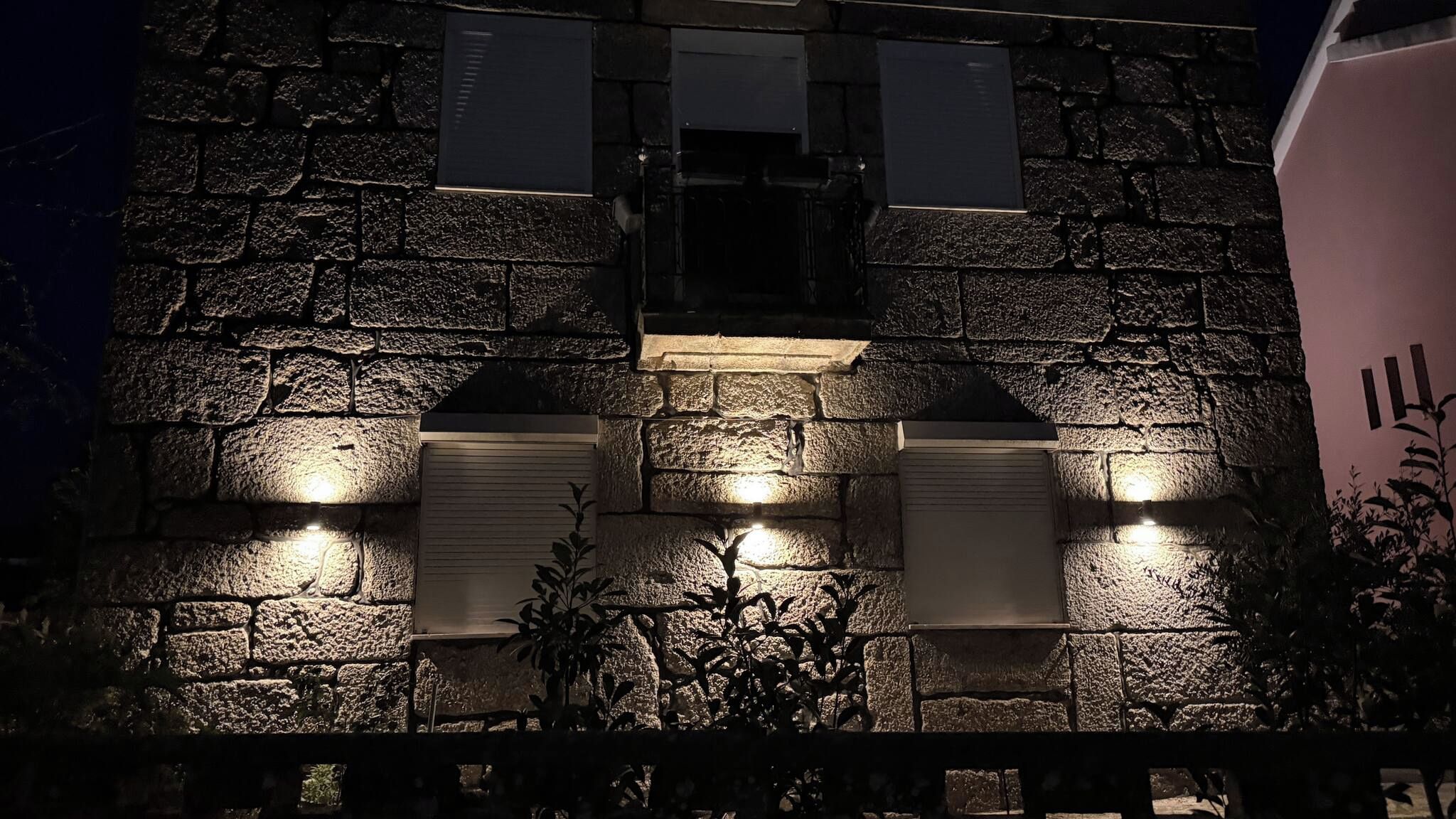 A stone building with illuminated windows and a plaque.