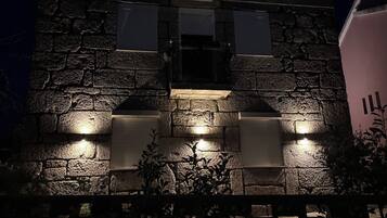 A stone building with illuminated windows and a plaque.