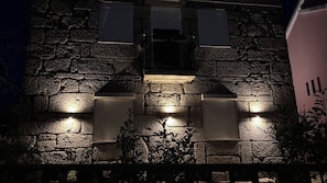 Un bâtiment en pierre avec des fenêtres illuminées et une plaque commémorative.