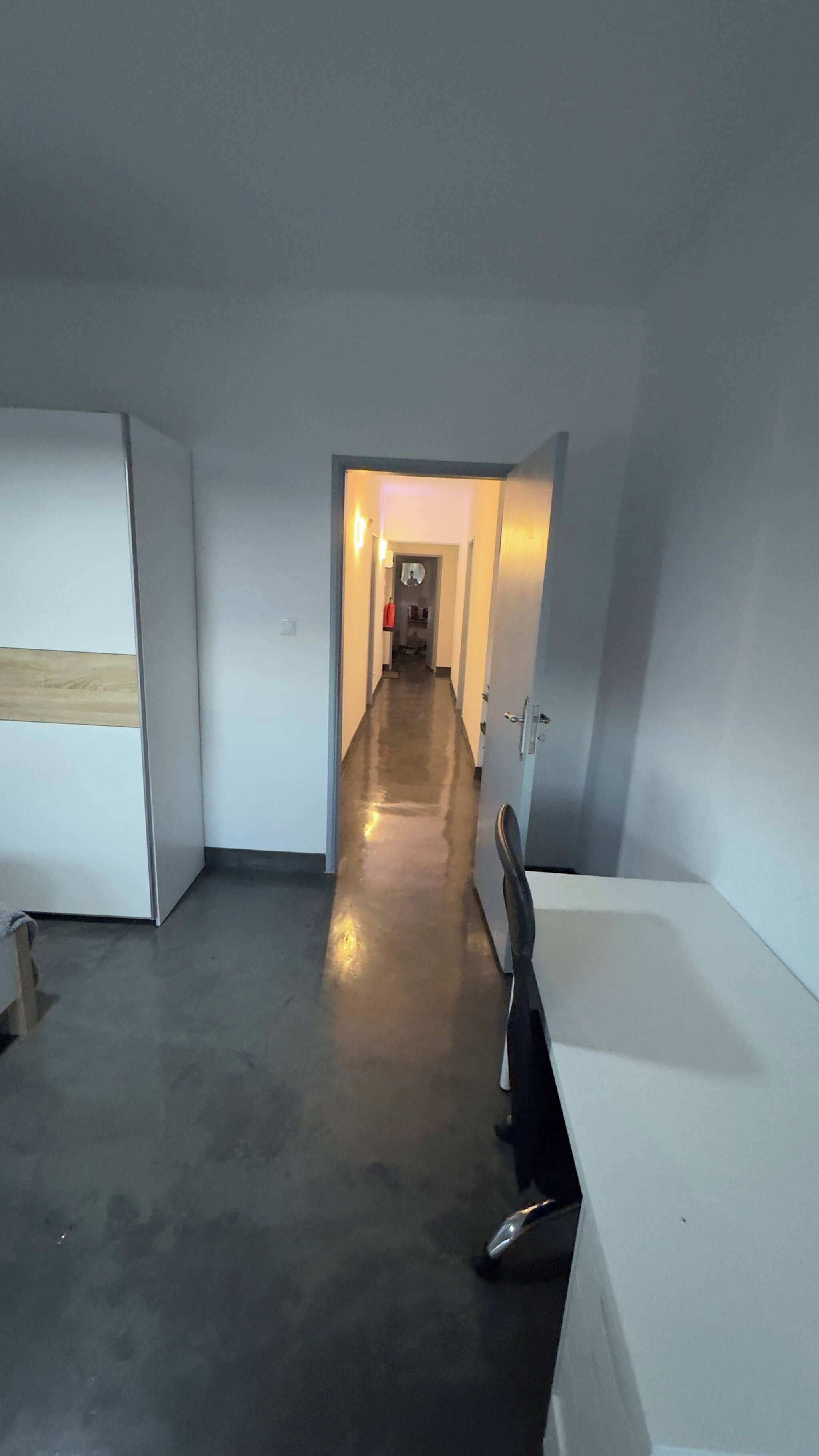 A hallway with a polished floor leading to a door at the end.