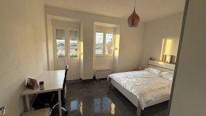 A bedroom with a bed, a desk, and a chair. There are two windows and a radiator. - Room-serene Condo Retreat in Vimieiro, P (Santa Comba Dao)
