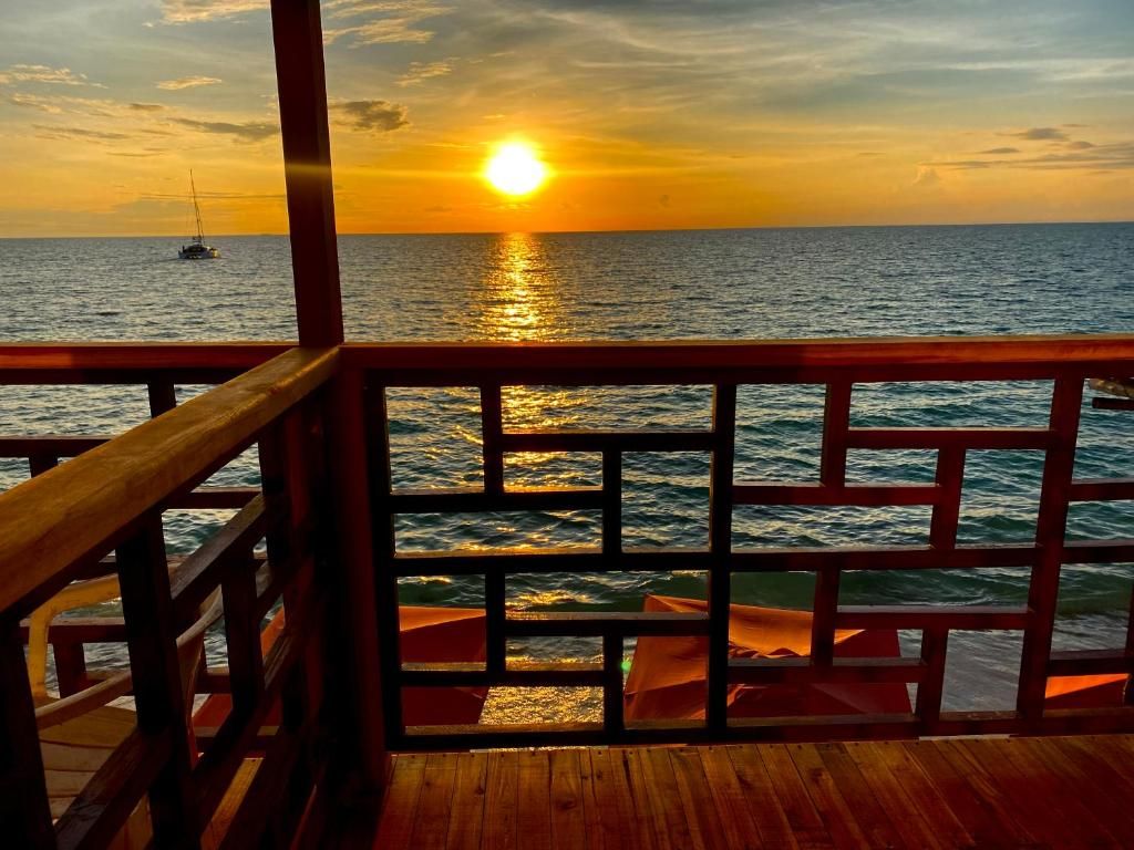 Una terraza de madera con barandilla que da a un cuerpo de agua durante el atardecer.