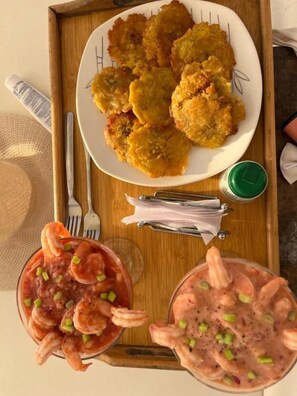 A tray with a plate of fried items, two glasses of shrimp soup, and a green condiment container. - Roma beach (Cartagena)