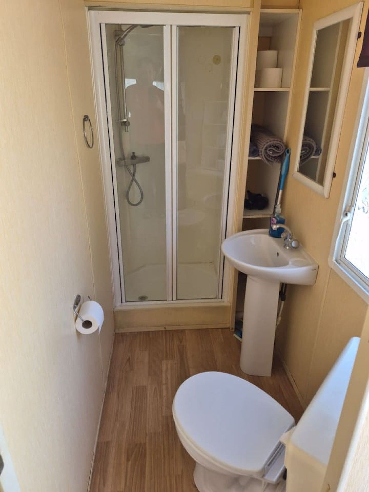 A compact bathroom with a glass-enclosed shower, a sink, and a toilet.