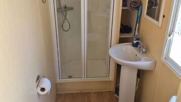 A compact bathroom with a glass-enclosed shower, a sink, and a toilet.