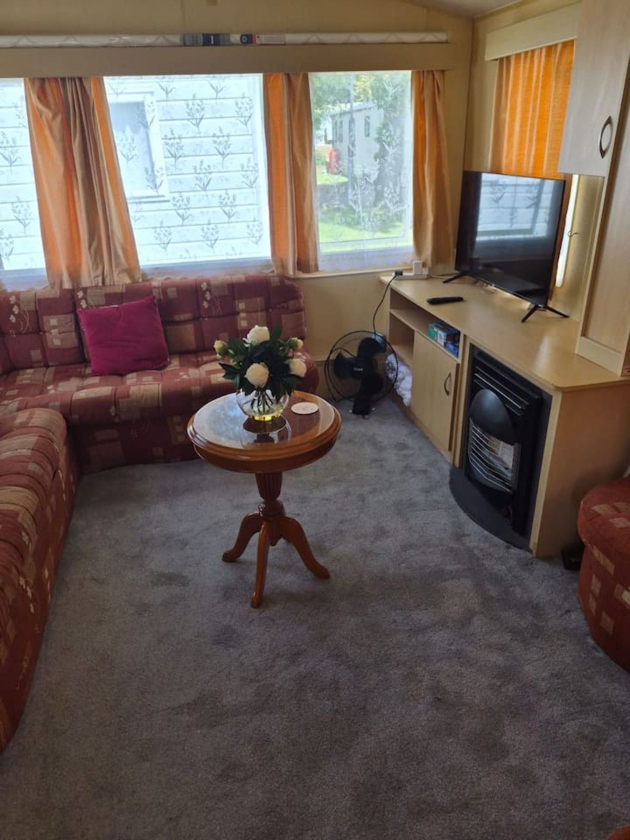 A living room with a sofa, a round table with a vase, a television, and a fireplace.