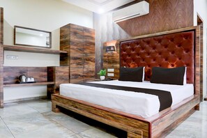 A modern bedroom with a large bed, built-in wardrobe, bedside lamp, and a potted plant.