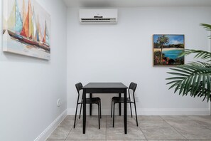 Ein Essbereich mit Tisch und Stühlen, einer Klimaanlage und zwei Bildern an den Wänden.