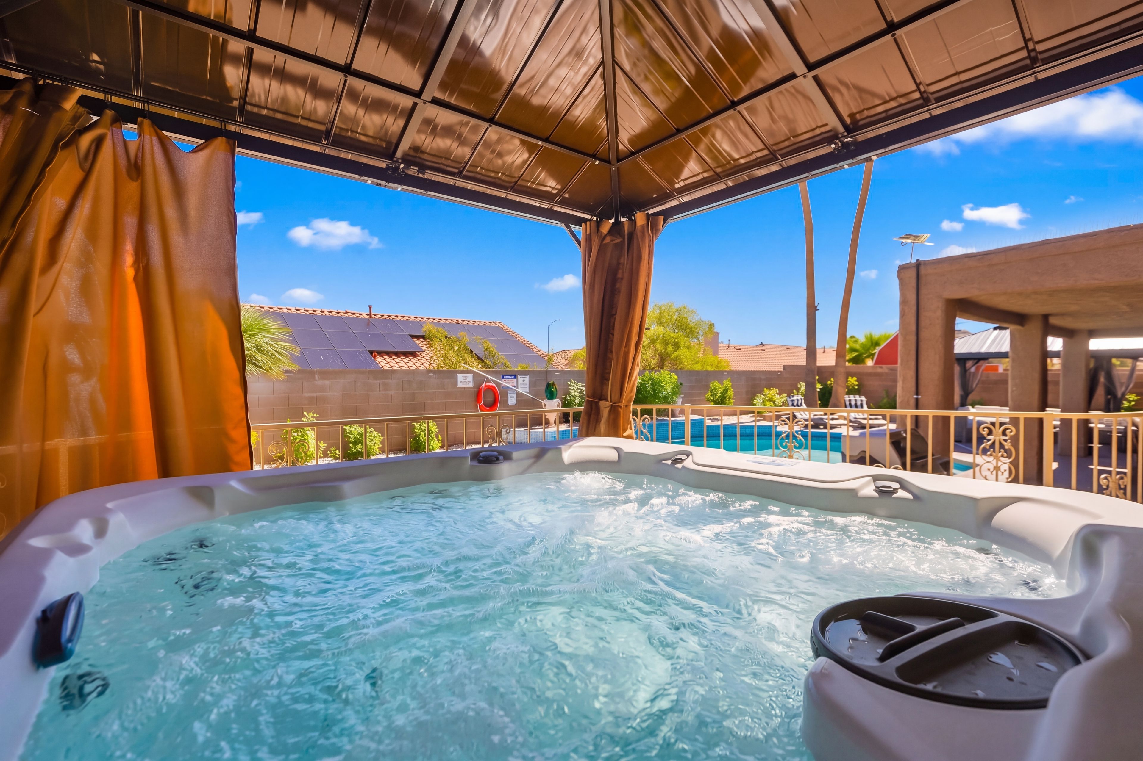 Covered outdoor hot tub with pool views and private resort-style backyard