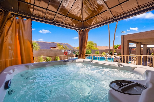 Covered outdoor hot tub with pool views and private resort-style backyard