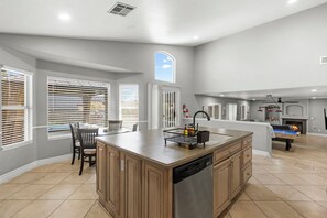 A modern kitchen with a central island, built-in dishwasher, and a dining area with chairs. - Pool & Hot tub • Game Room • King Beds • 16 Guests Max (Las Vegas)