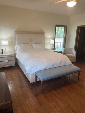 A bedroom with a large bed, bedside tables, a bench, a chair, and a window with blinds. - Round Hill Retreat-One Bedroom Apartment - Handicap Accessible (Round Hill)