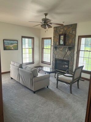 A living room with a sofa, armchair, coffee table, fireplace, and large windows. - Round Hill Retreat-One Bedroom Apartment - Handicap Accessible (Round Hill)