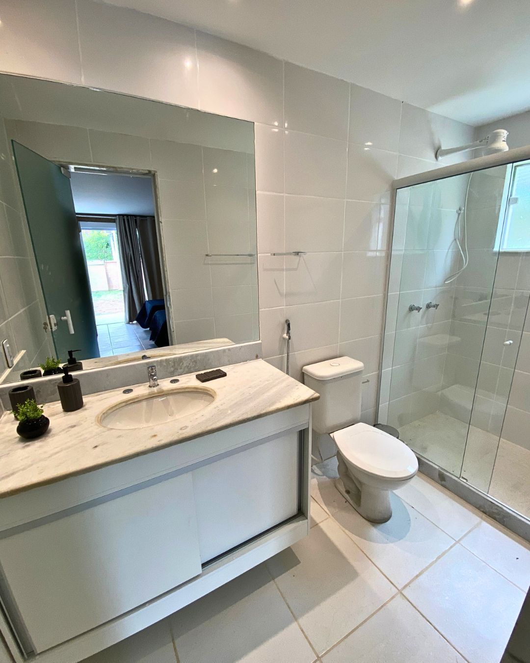 Une salle de bain moderne avec un grand miroir, un lavabo, des toilettes et une douche à parois de verre.