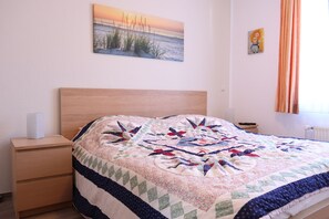 A bedroom with a bed, a nightstand, a bedside table, a lamp, and a painting on the wall. - Meerluft Boltenhagen Vacation Rental - Sünnslag Complex (Boltenhagen)