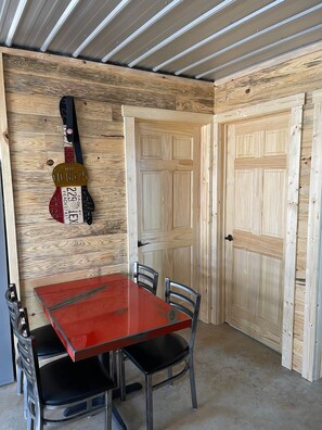 Ein Zimmer mit einem roten Tisch, Stühlen, Holzwänden und zwei geschlossenen Türen.