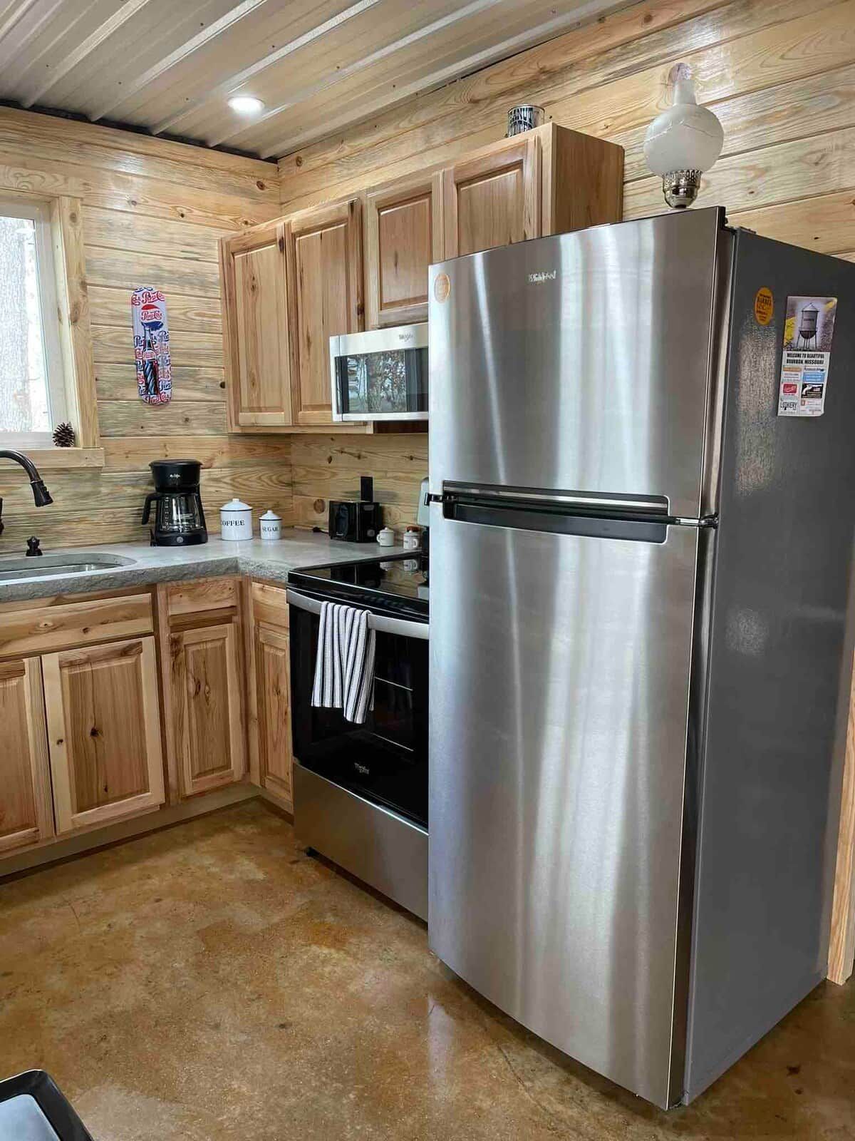 A kitchen with wooden cabinets, a stainless steel refrigerator, a microwave, a coffee maker, and an oven.