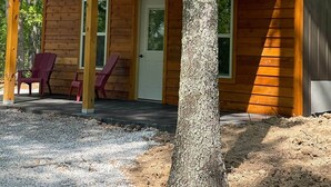 Eine Holzhütte mit Veranda, zwei Türen und zwei Stühlen.