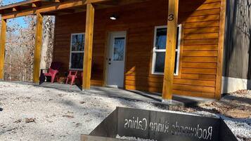 A cabin with a wooden exterior, a porch with chairs, and a sign indicating 'Rockwoods Ridge Cabins'.