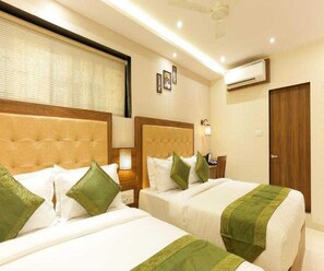 A hotel room with two beds, a nightstand, a lamp, and a door. - Collection O Chena Creek Godbandar (Mumbai)