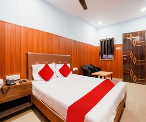 A hotel room with a bed, bedside table, telephone, and a small table with chairs. - Collection O Chena Creek Godbandar (Mumbai)