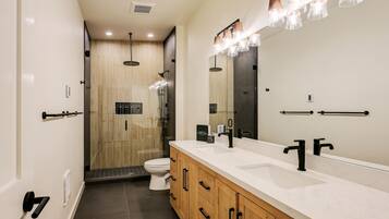 A modern bathroom with a large mirror, dual sinks, and a shower area.