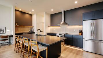 A modern kitchen with a central island, stainless steel appliances, and a dark cabinetry.