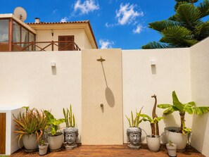 A courtyard with potted plants, a wooden deck, and a building with a balcony.