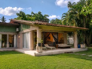 A house with a covered porch, a seating area with a bench and cushions, and a large window.