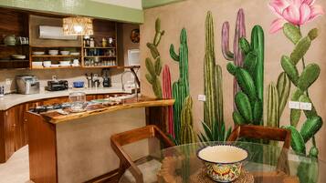 Una cocina con barra, armarios de madera y un mural con motivos de cactus en la pared.