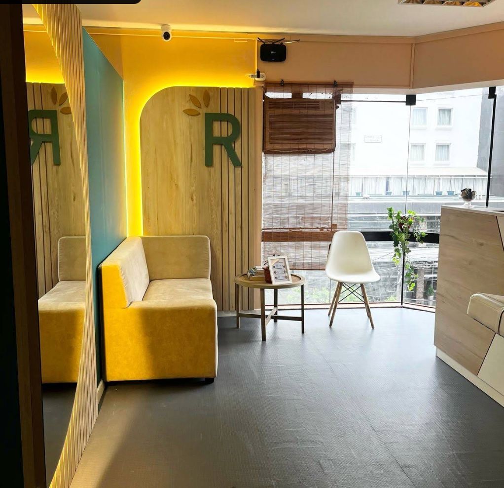 Una habitación moderna con un sofá amarillo, una silla blanca y una pequeña mesa con una planta.