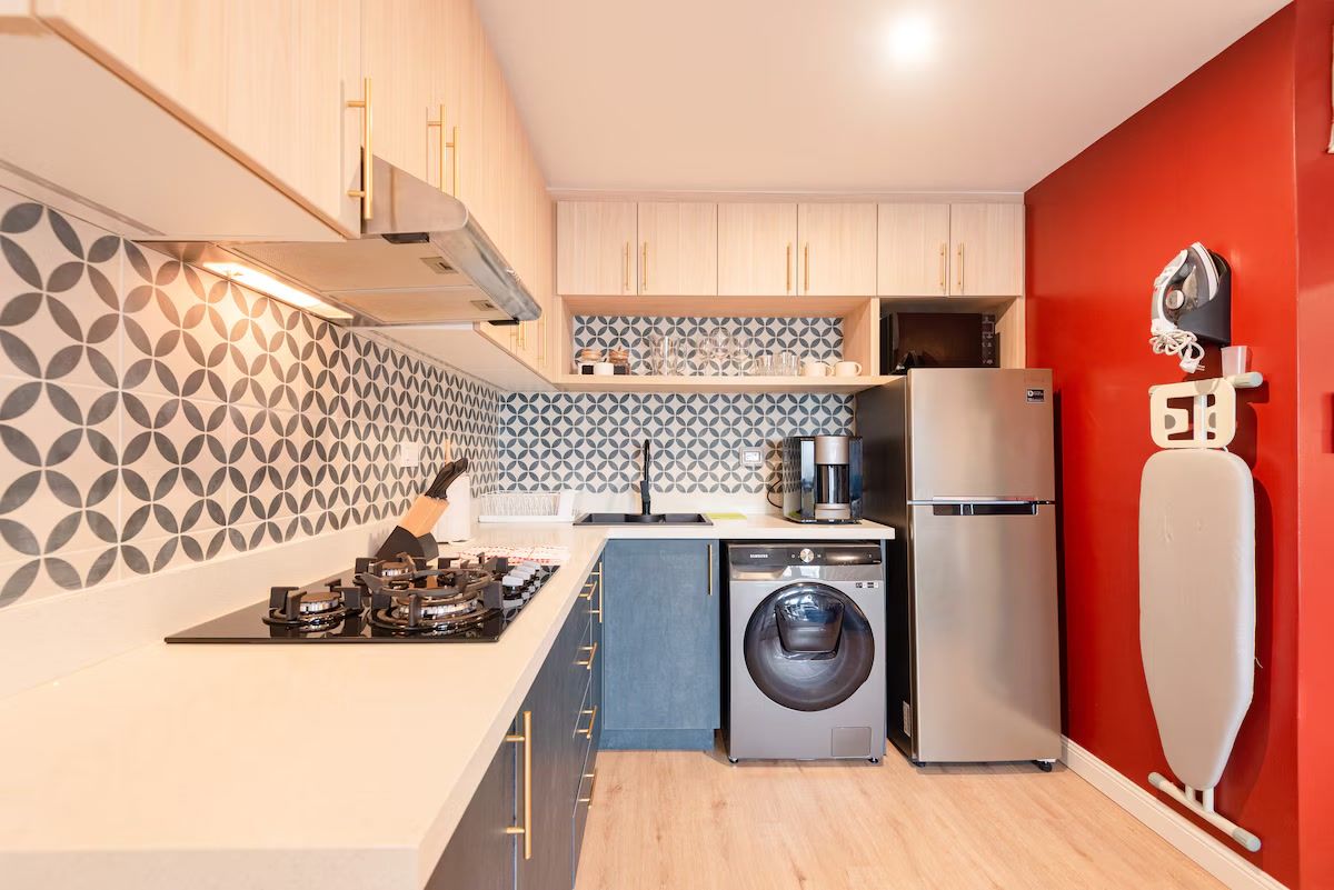 Une cuisine compacte équipée d’un lave-linge, d’un réfrigérateur et d’une machine à café.