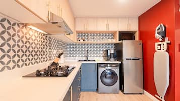 Une cuisine compacte équipée d’un lave-linge, d’un réfrigérateur et d’une machine à café.