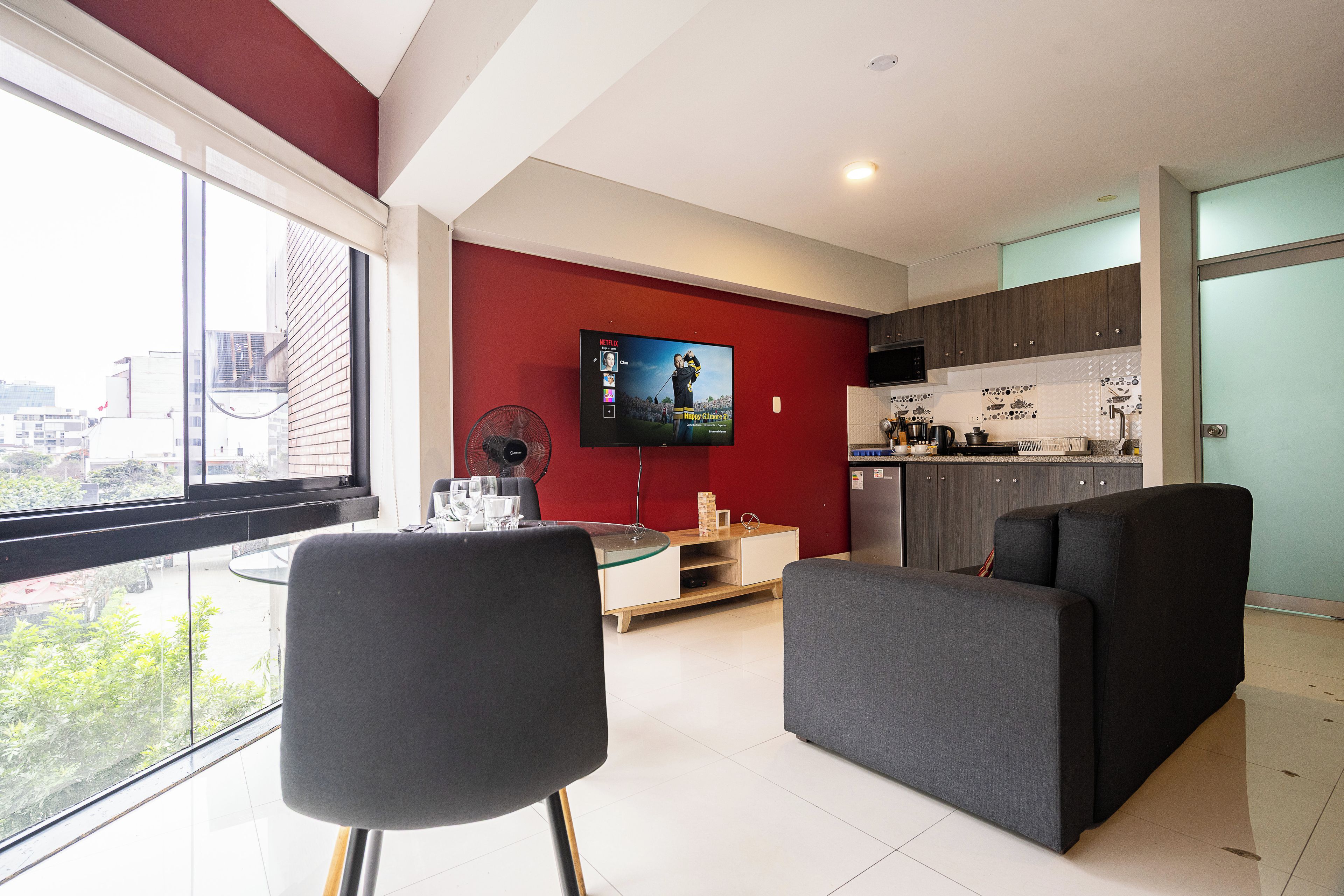 Una sala de estar moderna con un televisor grande, un comedor y una cocina.