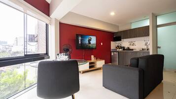 Una sala de estar moderna con un televisor grande, un comedor y una cocina.