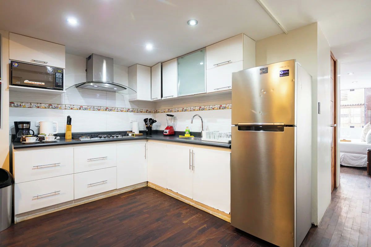 Una cocina moderna con armarios blancos, un refrigerador de acero inoxidable y un microondas.