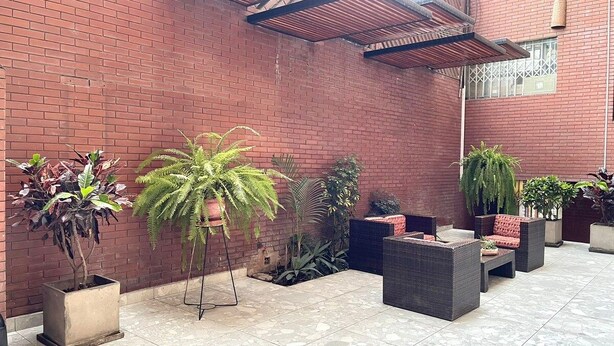 Un espace extérieur aménagé en patio, avec des murs en briques, des plantes en pot et du mobilier de jardin.