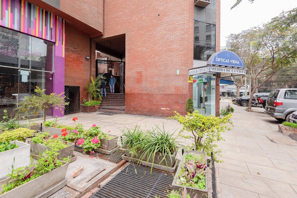 Un edificio con fachada de ladrillo, entrada de vidrio y un letrero que dice 'OPTICAS VIENA'.