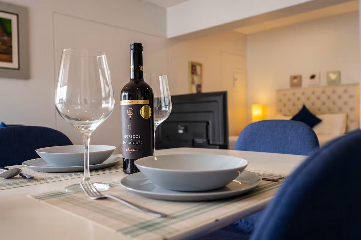 A dining table with a bottle of wine, glasses, and plates set for a meal.