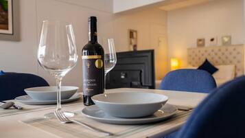 A dining table with a bottle of wine, glasses, and plates set for a meal.