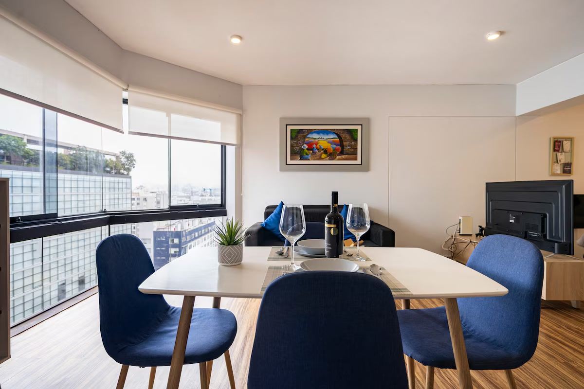 Un comedor moderno con una mesa, sillas y un cuadro en la pared.