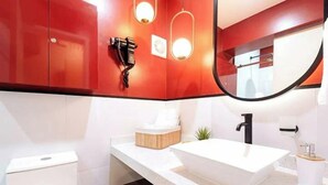 Une salle de bain moderne avec un meuble rouge, un lavabo blanc et un miroir.
