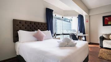 Een hotelkamer met een groot bed, een bureau en uitzicht op een gebouw.