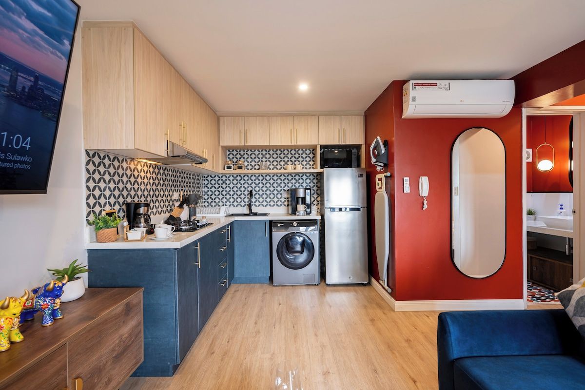 Eine kleine Küche mit Waschmaschine, Kühlschrank und Mikrowelle.