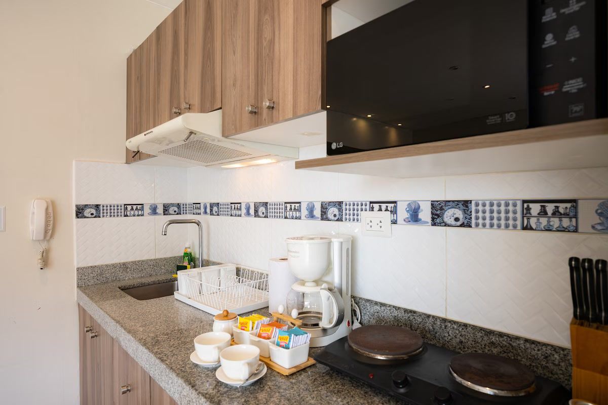 Una cocina con cafetera, tazas y estufa.