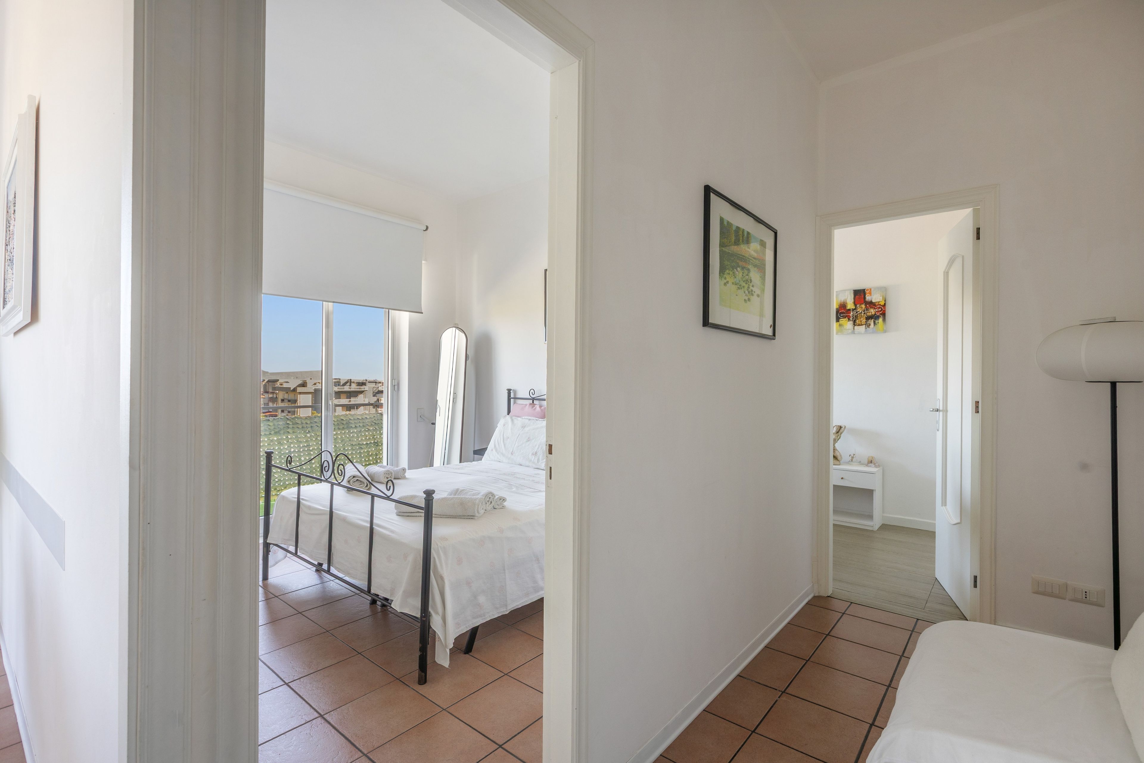 Een slaapkamer met een bed, een badkamer met een wastafel en spiegel, en uitzicht op het omliggende gebied.