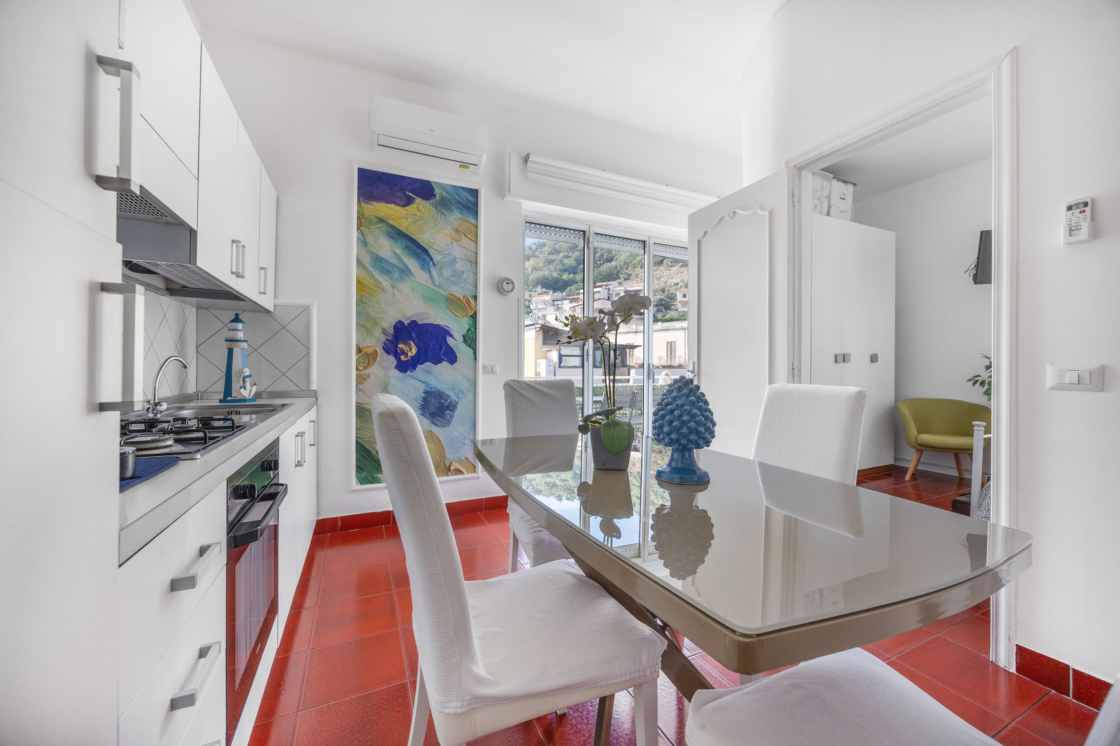A modern kitchen with a dining area, a large window, and a view of the city.