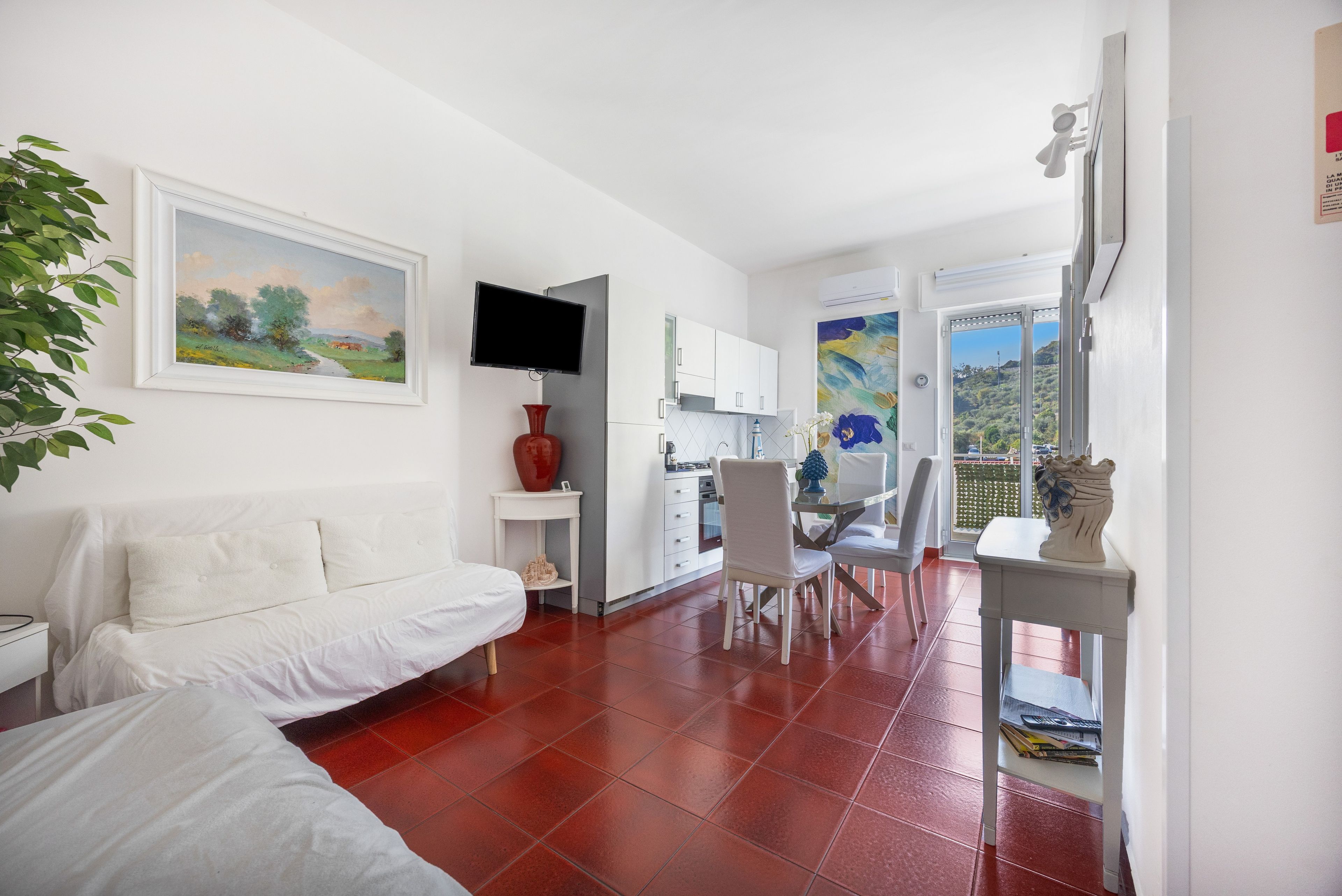 Una sala moderna con un sofá blanco, un televisor de pantalla plana y un comedor con mesa y sillas.