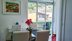 A dining area with a table and chairs, a potted orchid, and a painting on the wall. - Apartment 'Ekaterina House 2 Minuti Dal Mare' (Brolo)