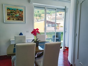 Ein Essbereich mit Tisch und Stühlen, einer Topf-Orchidee und einem Bild an der Wand.